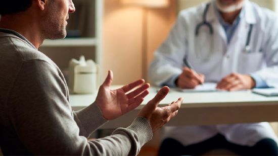 Мужчина жестикулирует, разговаривая с врачом в медицинском кабинете